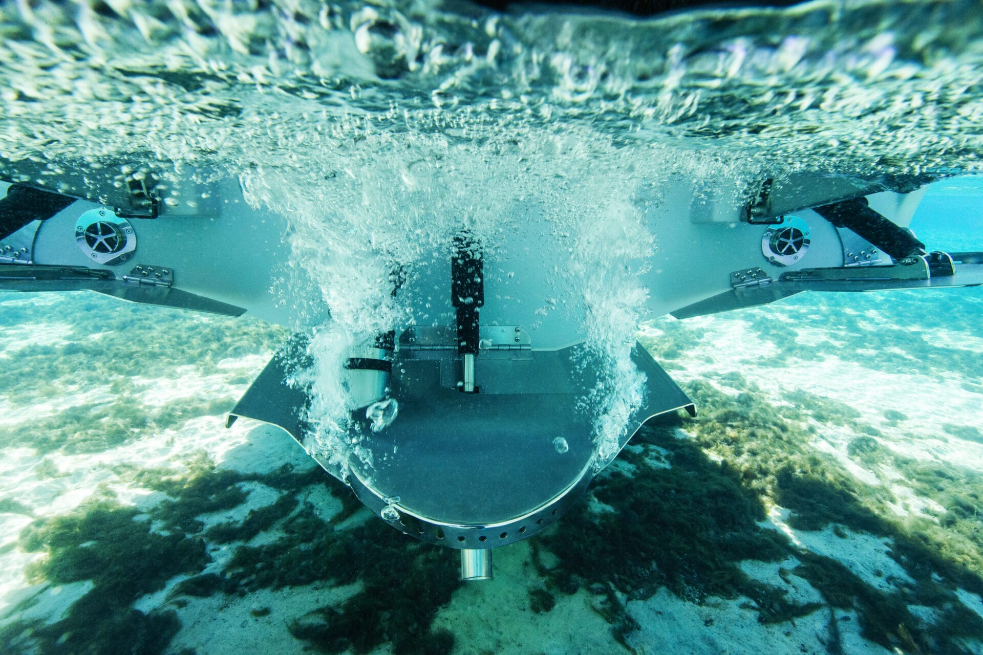 Underwater view of a submersible or aquatic vehicle with propulsion system activated, creating bubbles and turbulence in clear water over a sandy, algae-covered seabed. Imagine how you could customize your ride to explore the depths with personalized flair and advanced technology.