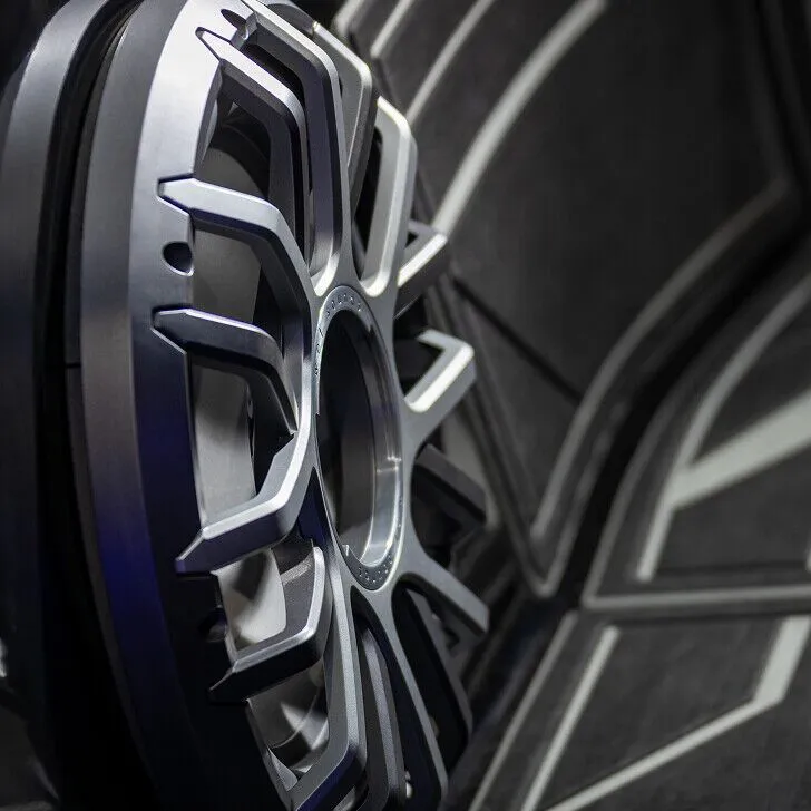Close-up of a silver alloy car wheel rim against a dark, patterned background.