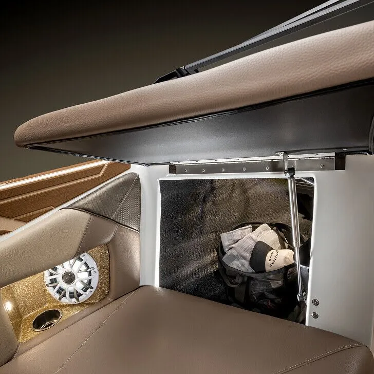 Open storage compartment under a brown cushioned seat, revealing a bag inside; speaker and cup holder are visible on the side panel.