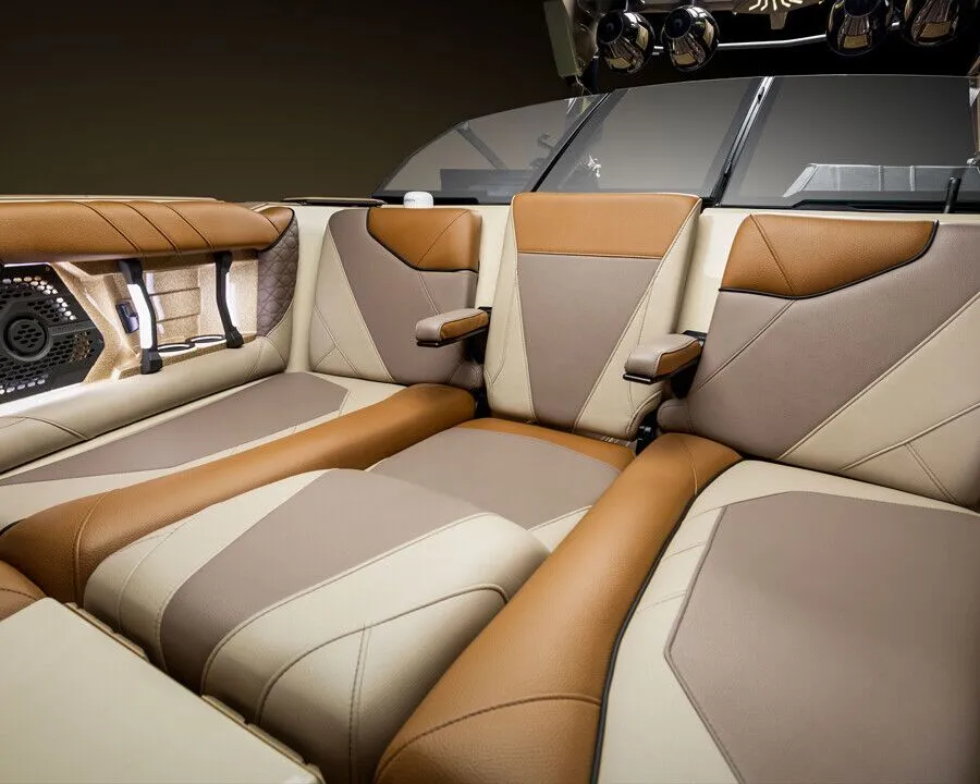 Brown and beige leather seats with armrests and built-in speakers in a modern Centurion Nv Series boat interior, seen from the rear facing forward.