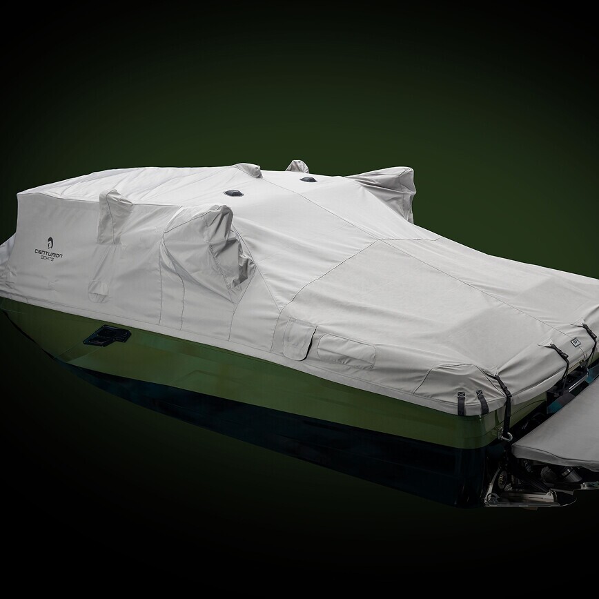 A Centurion Ri Series boat covered with a fitted, light gray protective cover against a dark background.