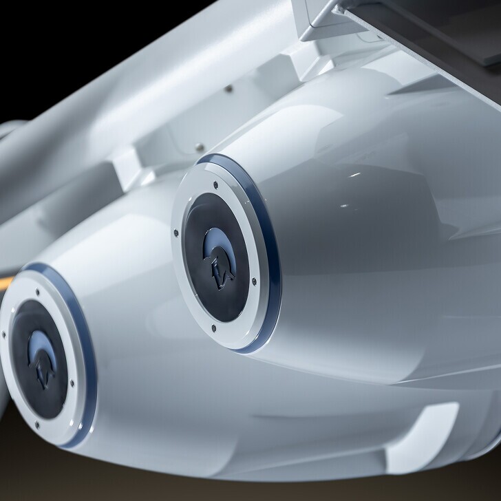 Close-up view of two cylindrical white mechanical components with circular blue and black detailing, mounted side by side on a metallic structure.