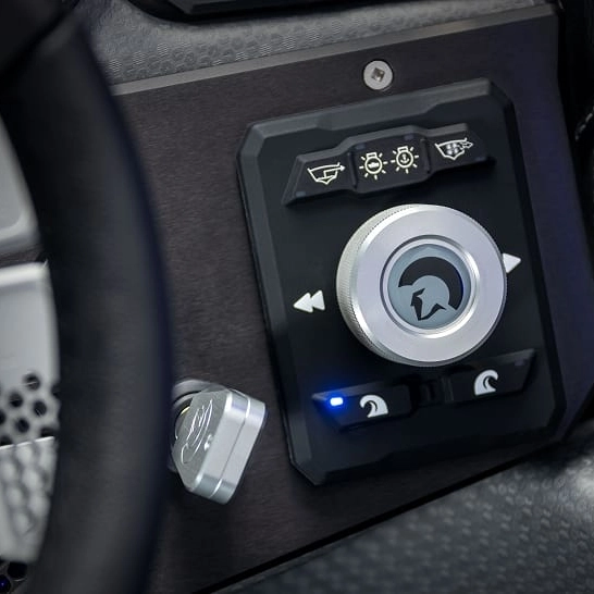 Close-up of a control knob from the Ri Series, featuring icons for lights and other functions on a vehicle dashboard, with blue indicator lights and metallic components highlighting its Features Personal.