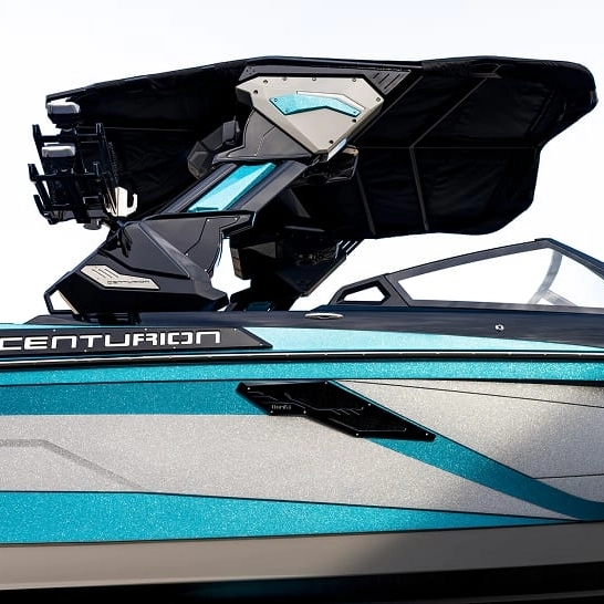 Side view of a blue and silver Centurion Ri Series boat, featuring a modern wakeboard tower with black and teal accents against a plain background. This model features personal touches for an enhanced boating experience.