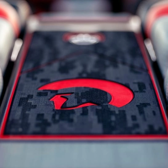 Close-up of a car interior detail from the Ri Series, featuring a red Spartan helmet logo on a black and gray patterned surface with red trim for a bold, personal touch.