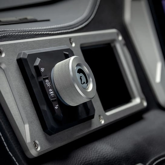 Close-up of a metallic rotary knob with icons for lights and windshield functions on the Nv Series dashboard, designed to Make The Features Personal with customizable controls.