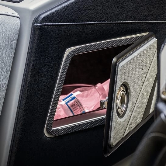 A close-up of an open compartment in a car door highlights the personal features of the Nv Series, with a pink plastic water bottle stored inside.