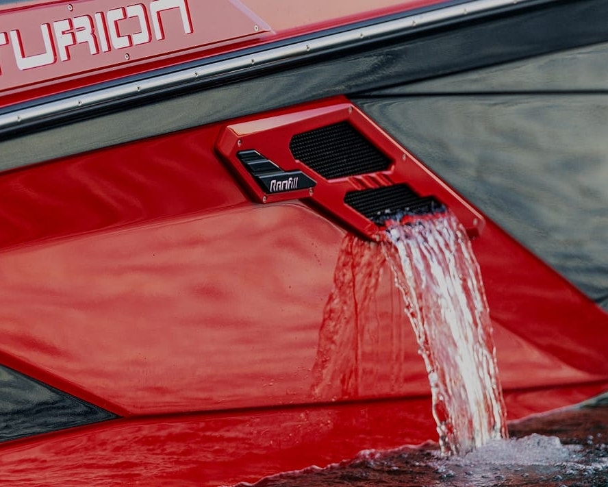 Close-up of a red boat hull with water flowing out of a Centurion RAMFILL vent labeled 