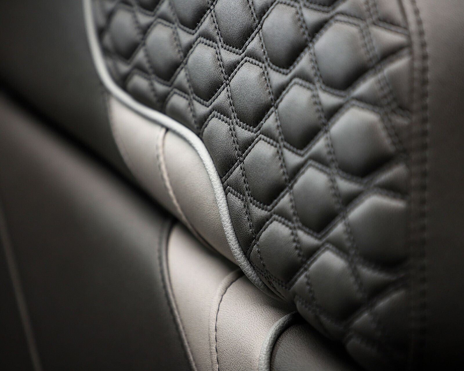 Close-up of a car seat with quilted black leather upholstery and contrasting stitching details.