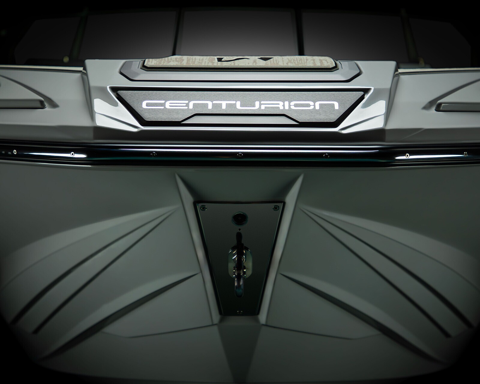 Close-up view of the front of a Centurion boat, showing the brand name illuminated in white lettering and angular design details.