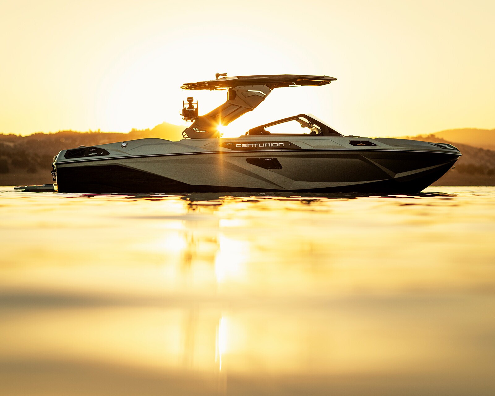 A motorboat floats on calm water at sunset, with golden sunlight reflecting on the boat and water’s surface.