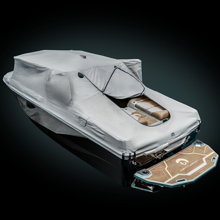 A covered speedboat with a beige protective cover, partially revealing tan leather seats and a wooden swim platform at the rear, set against a dark background.