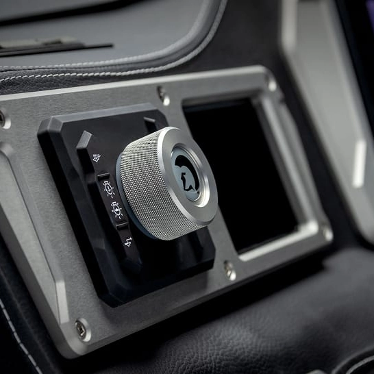 Close-up of a metallic rotary knob with icons for lights and windshield functions on the Nv Series dashboard, designed to Make The Features Personal with customizable controls.