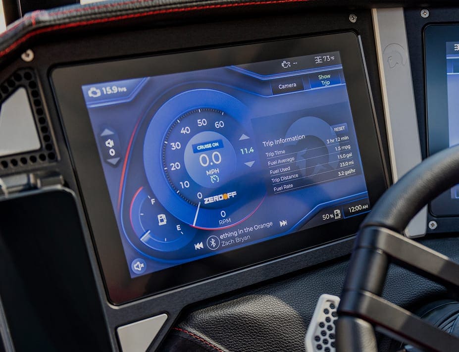 Close-up of a car dashboard display showing speedometer, trip information, cruise control status, music by Zach Bryan, and a comparison to Centurion Boat fuel efficiency.