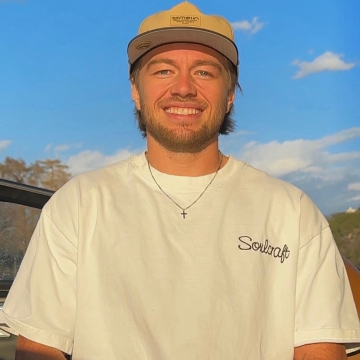 Trevor Miller, a man with a beard and mustache wearing a tan cap, white 