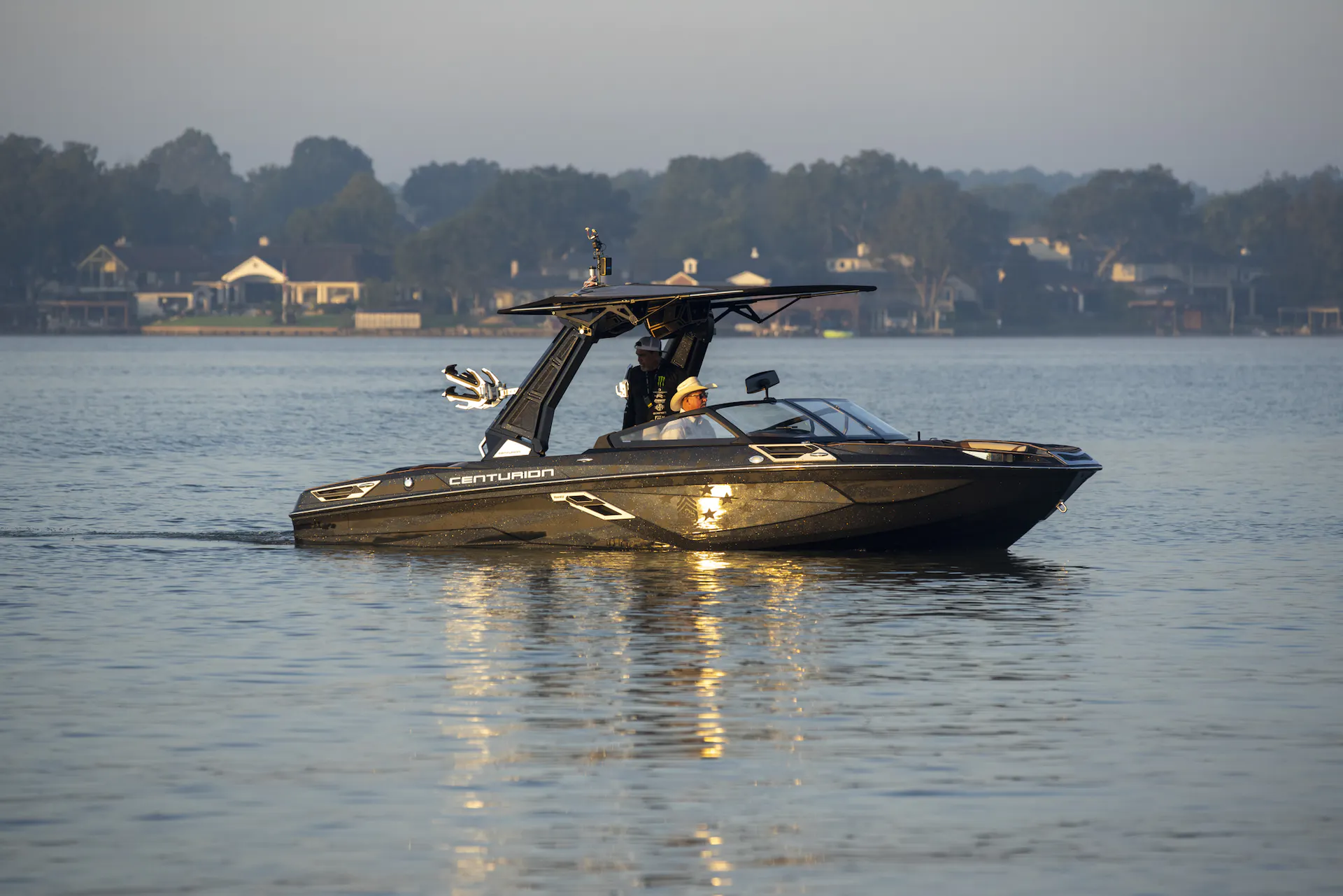 A man is wakesurfing behind a wakeboat on a lake.