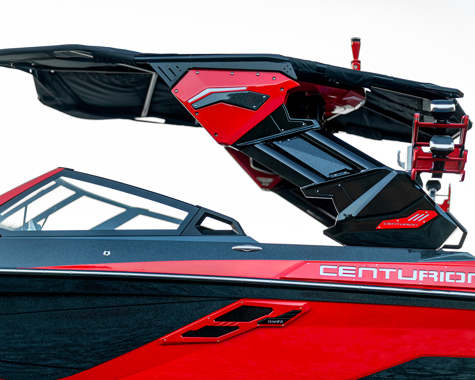 Close-up of a red and black Centurion Ri230, showing the side view of the wakeboard tower and part of the windshield against a white background.