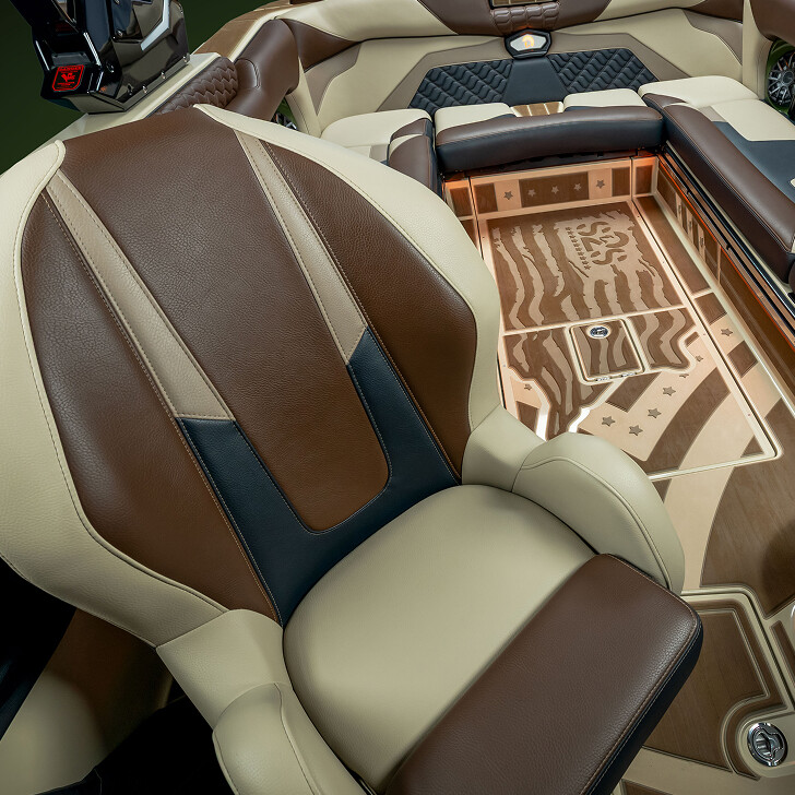 Captain’s chair and interior seating of a luxury boat, with tan, brown, and black leather upholstery and wood-patterned flooring featuring star and stripe designs.