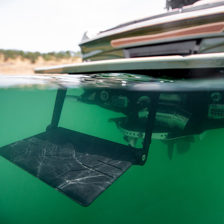 A submerged swim platform extends from the back of a boat into clear green water, partially showing underwater mechanical parts.