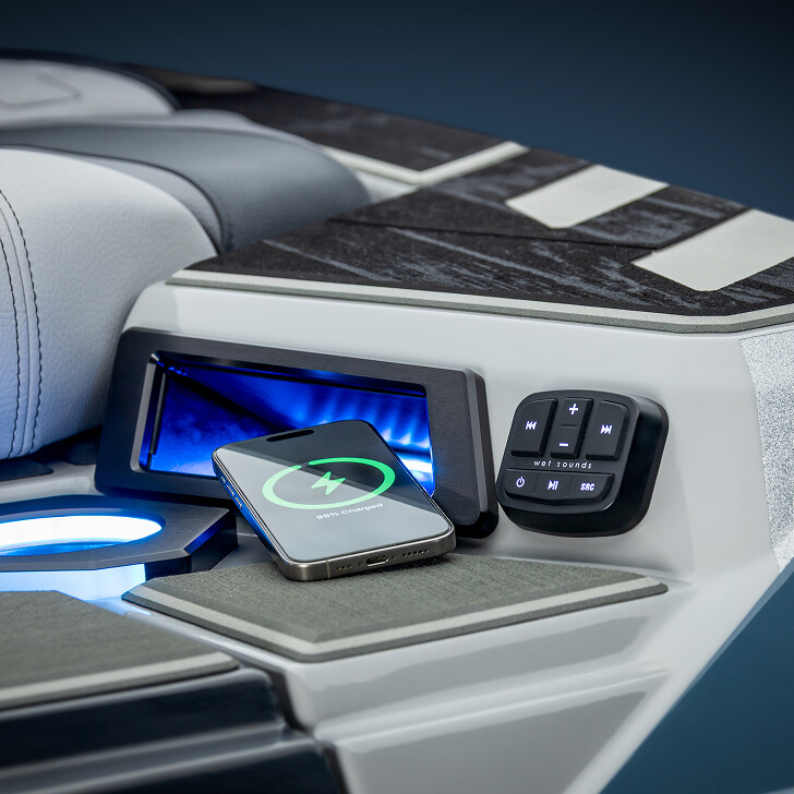 A smartphone wirelessly charging on a boat's console next to a control panel and LED-lit compartment.