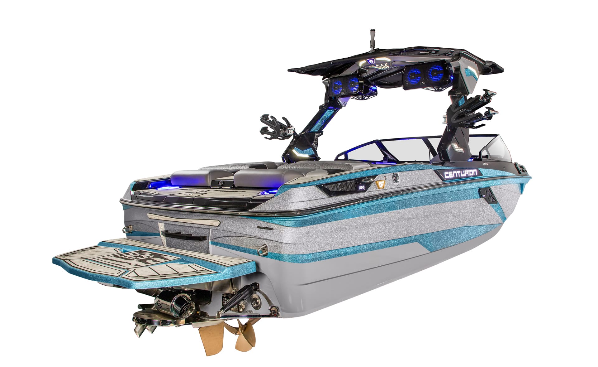 A modern Centurion Ri245 wakeboard boat with blue and gray exterior, rear swim platform, exposed propeller, tower speakers, and padded seating.