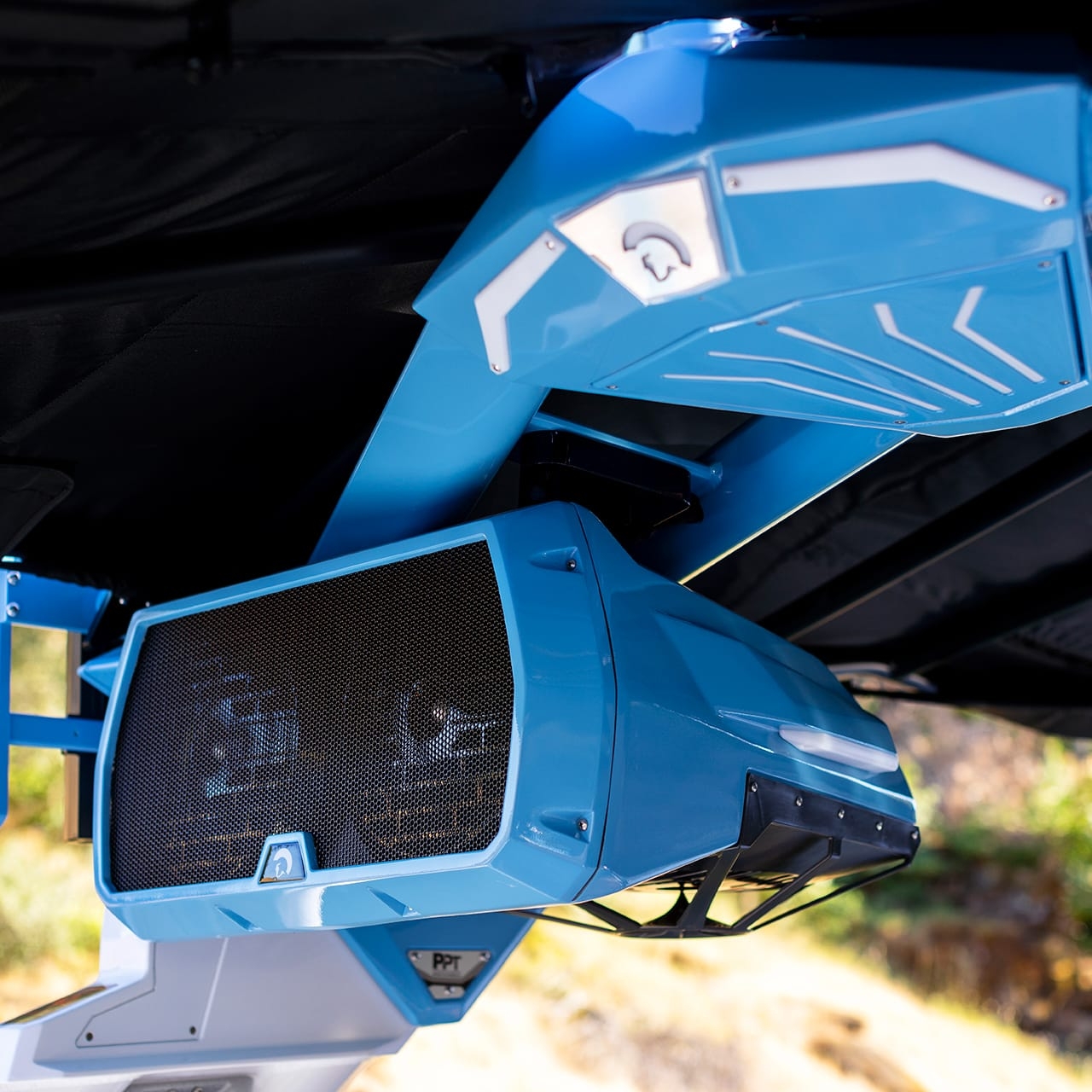 Close-up of a blue speaker system mounted under the canopy of a Centurion Ri245 with outdoor scenery in the background.