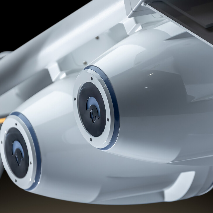 Close-up view of two cylindrical white mechanical components with circular blue and black detailing, mounted side by side on a metallic structure.