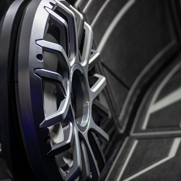 Close-up of a silver alloy car wheel rim against a dark, patterned background.