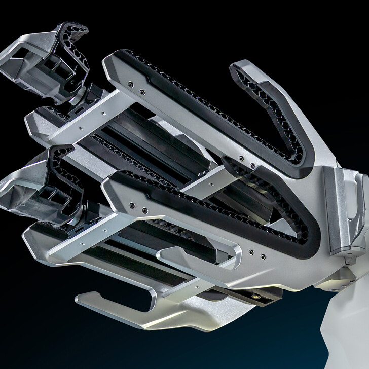 Close-up view of a metallic robotic gripper with multiple articulated fingers, shown against a dark background.