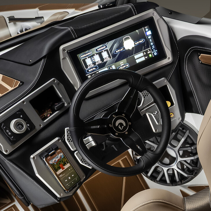Modern boat dashboard with touchscreen controls, steering wheel, cupholder, mounted smartphone, and various buttons and dials on a brown and black panel.