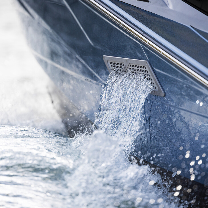 Water flows out of a drain on the side of a boat, creating splashes in the surrounding water.