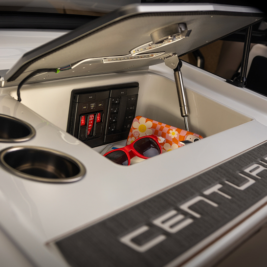 An open compartment on the boat reveals electrical switches, a floral-patterned item, and red sunglasses; part of the 