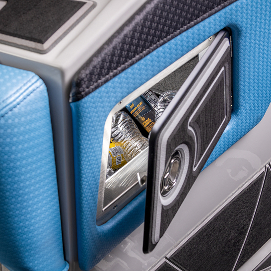 A small compartment with an open door reveals bottled water and energy drinks inside, set within a blue and black upholstered surface—part of the Fe Series that features personal storage solutions.