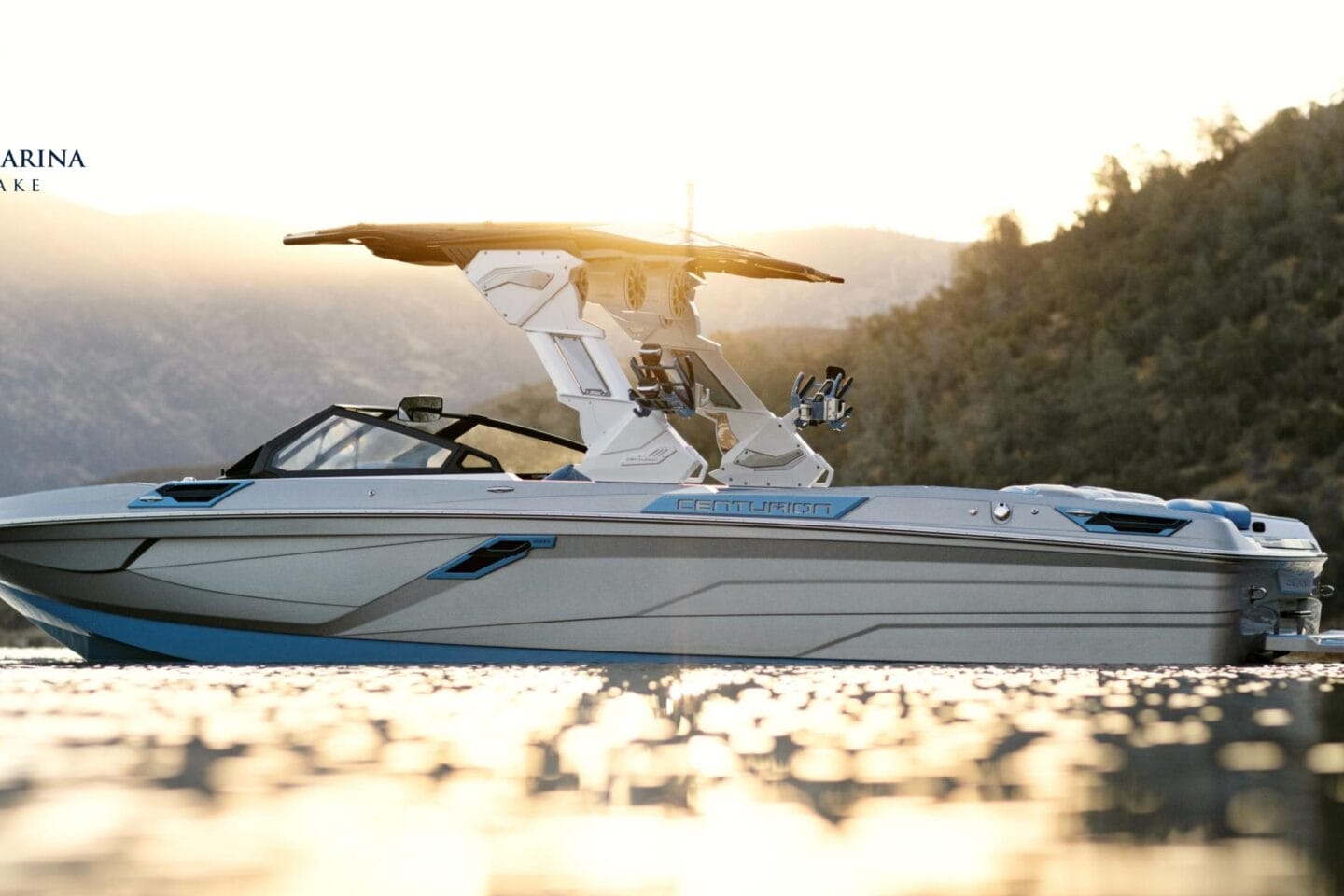 A sleek motorboat is on a lake at sunset with hills in the background. The logo reads 