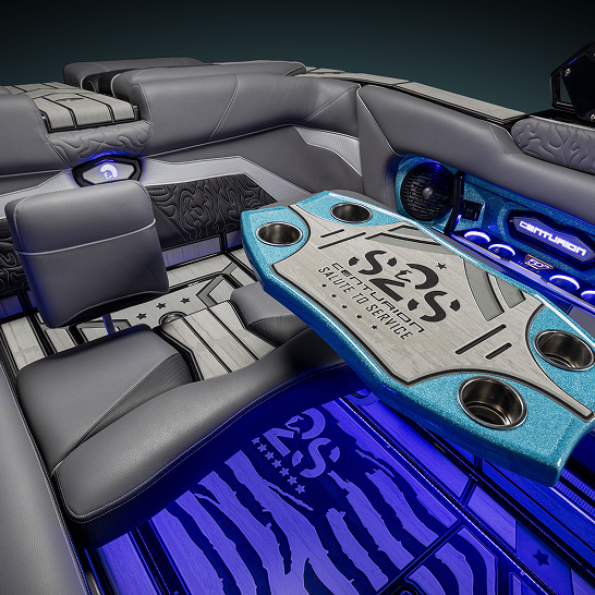 Interior of a luxury Ri Series boat with gray leather seating, blue LED lighting, and a custom table featuring cup holders. “S2S” branding on the table and floor highlights the Features Personal touch throughout.