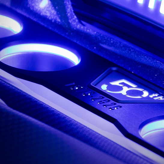 Close-up of a metallic car interior detail illuminated by blue lights, featuring a 