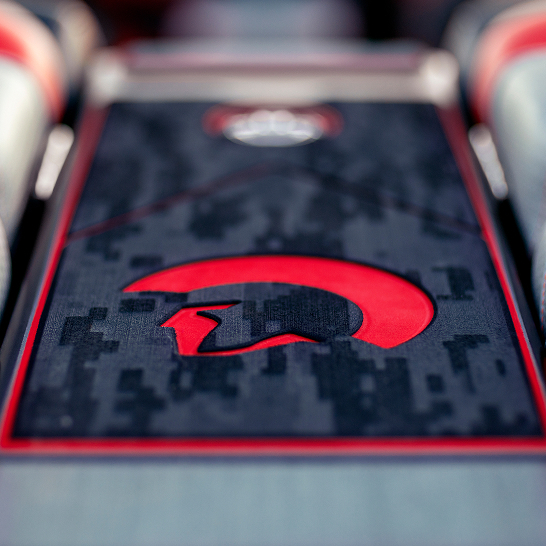Close-up of a car interior detail from the Ri Series, featuring a red Spartan helmet logo on a black and gray patterned surface with red trim for a bold, personal touch.