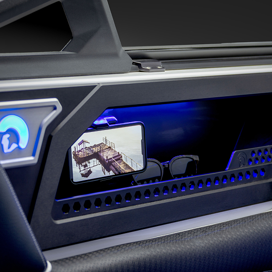 A smartphone displaying a dock scene sits in a compartment with blue accent lighting beside sunglasses inside a modern Ri Series vehicle interior, highlighting its Features Personal touch.