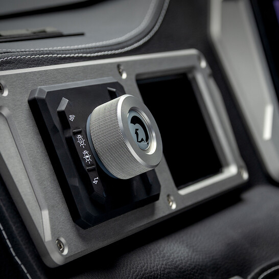 Close-up of a metallic rotary knob with icons for lights and windshield functions on the Nv Series dashboard, designed to Make The Features Personal with customizable controls.