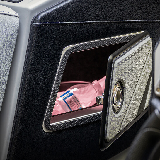 A close-up of an open compartment in a car door highlights the personal features of the Nv Series, with a pink plastic water bottle stored inside.