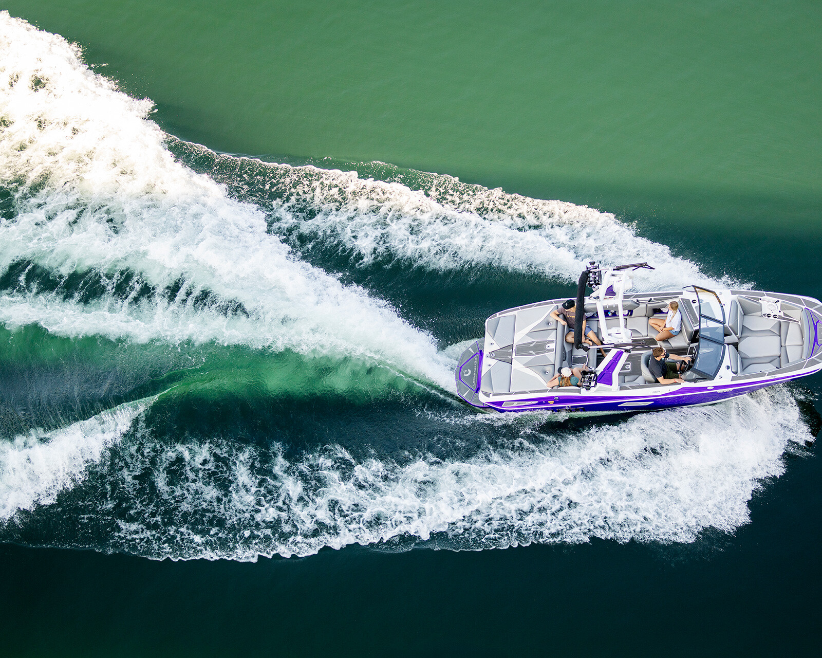 A purple and white Centurion Nv233 speedboat with people on board glides through green water, leaving a curved wake behind it.