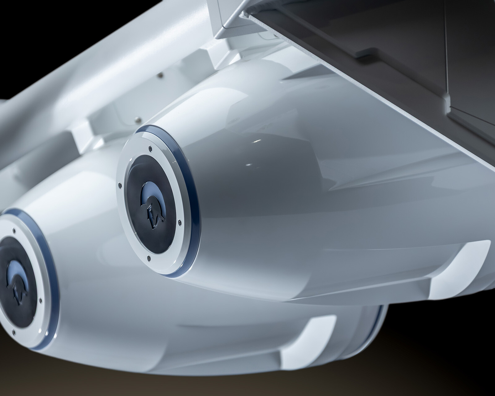 Close-up view of two white cylindrical pods attached under an aircraft wing, featuring circular hatches and a sleek, modern design reminiscent of the streamlined aesthetics found on a Centurion Nv213.