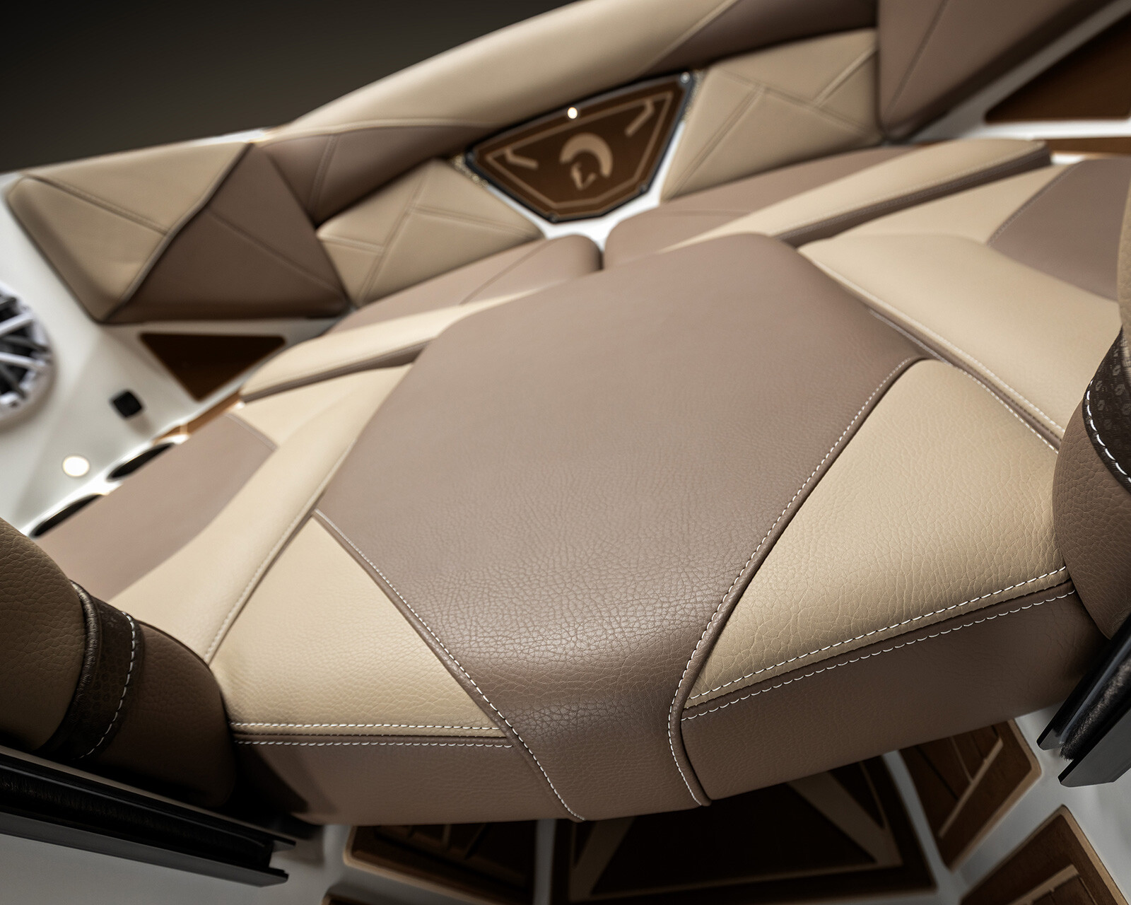 Close-up view of beige and brown leather seats with visible stitching in the Centurion Nv213, accompanied by a speaker and geometric panel design in the background.