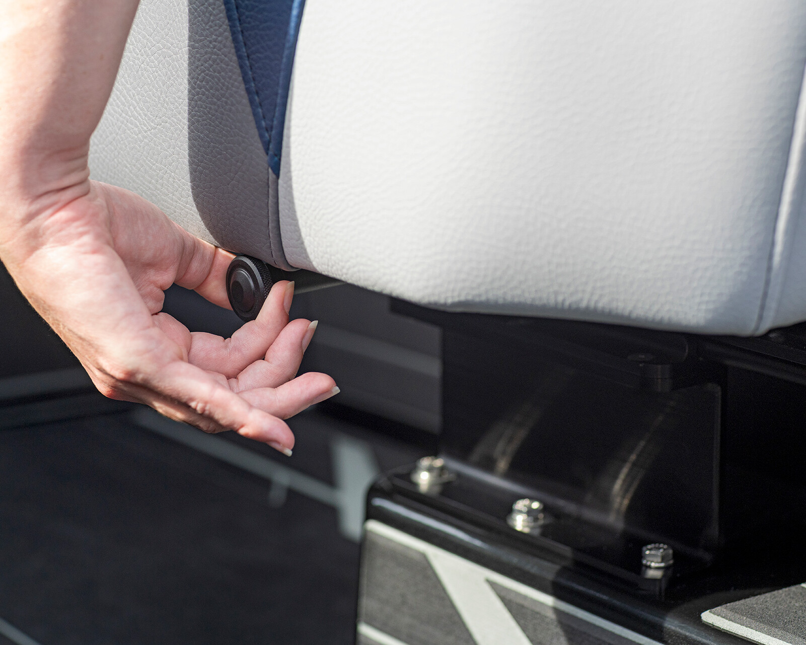 A person adjusts a knob under the edge of a gray seat on a Centurion Nv233, likely to modify the seat's position or height.