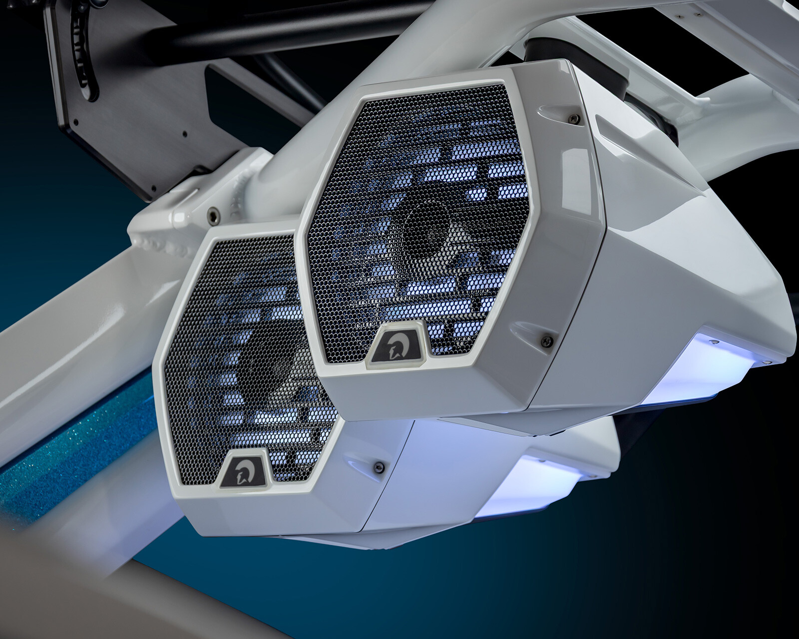 Close-up of two white hexagonal outdoor speakers mounted on a metal frame against a dark blue background, typically found on the Centurion Nv243 Surf Boat.