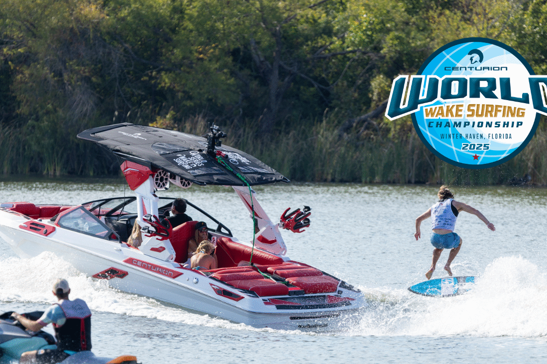 A person wake surfing behind a white and red speedboat on a lake with spectators nearby; World Wake Surfing Championship 2025 logo is displayed.