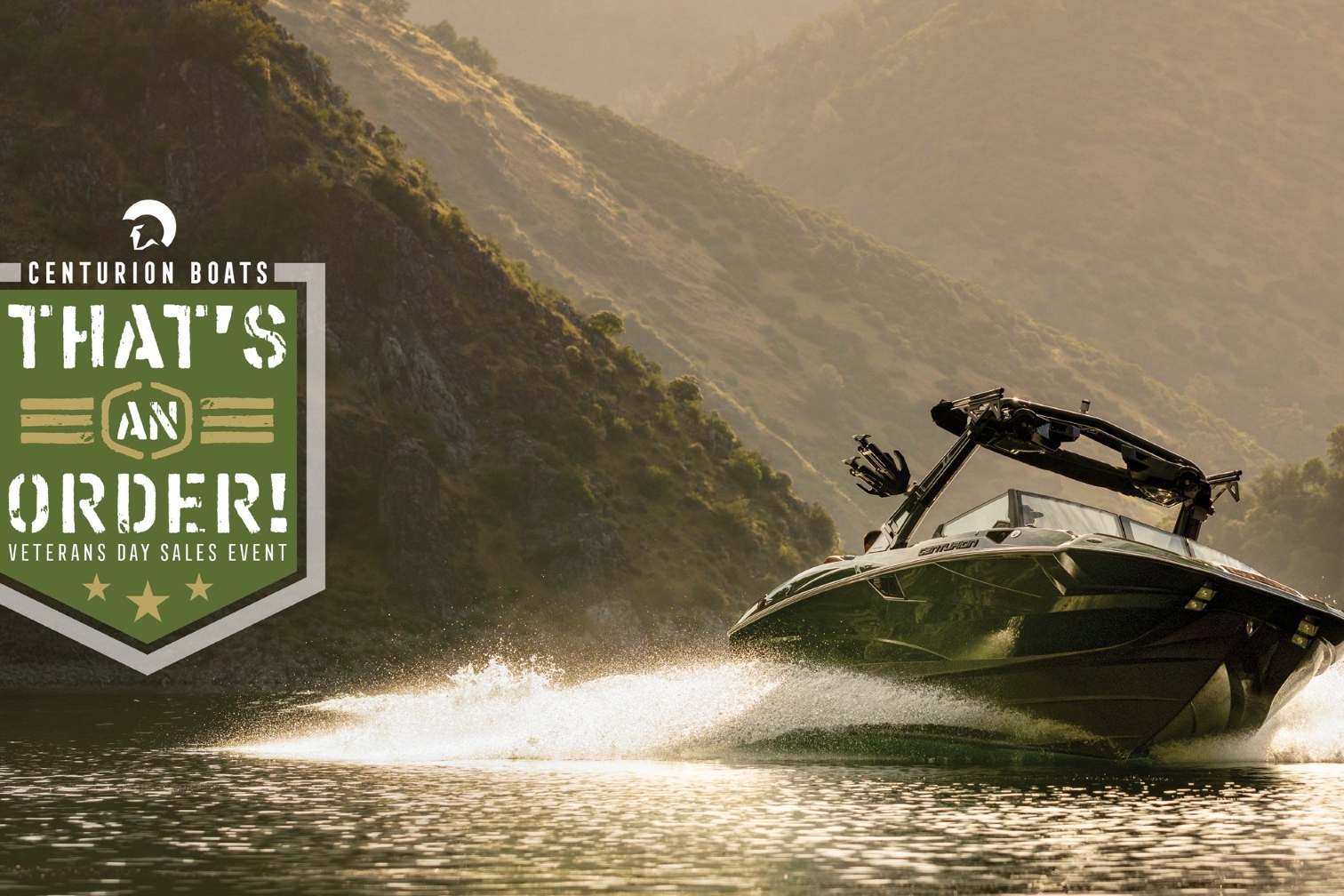 Speedboat moves quickly on a lake with mountains in the background; on the left, a Centurion Boats Veterans Day Sales Event badge reads “That’s an Order!”.